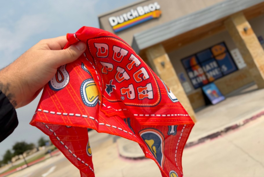 hand holding up a red bandana in front of a store