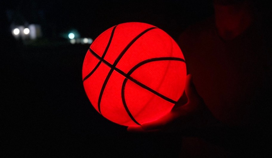 hands holding glow in the dark basketball in dark