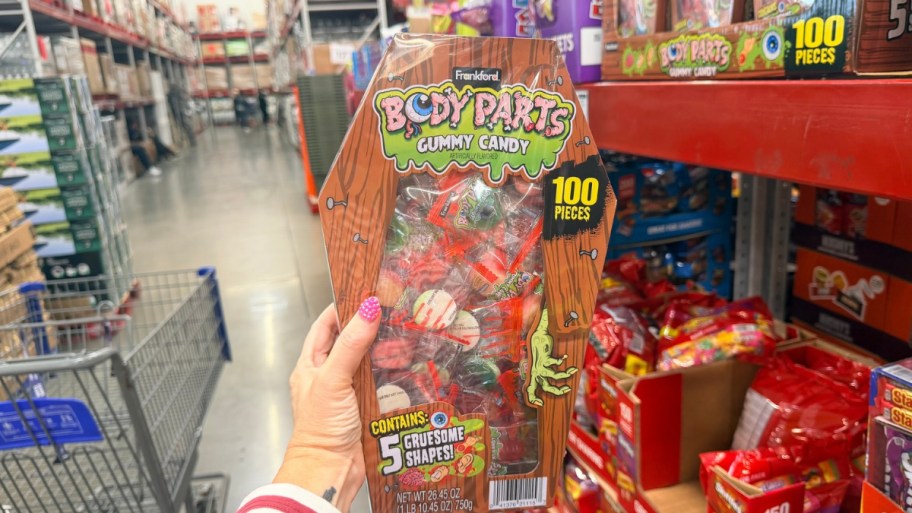 a womans hand holding a coffin shaped box of gummy body parts candiy