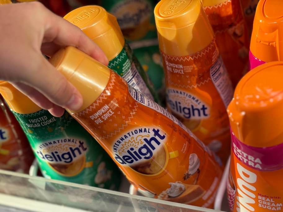 taking a bottle of creamer from a store's refrigerator case