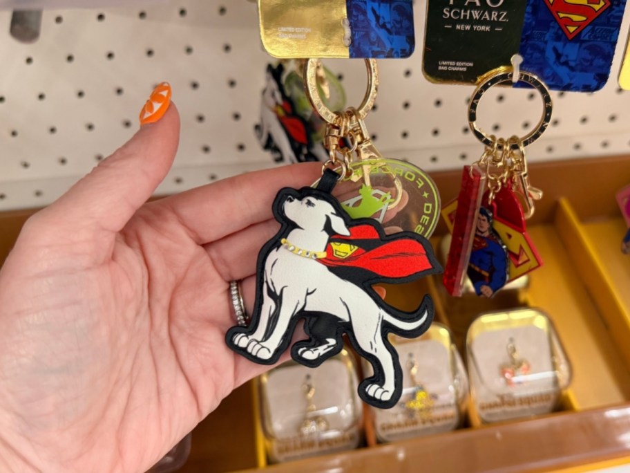 womans hand holding a krypto bag charm