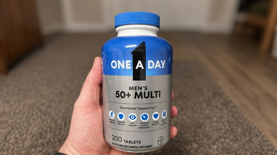 mans hand holding a 200 count bottle of multivitamins