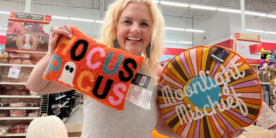 woman holding up orange hocus pocus and rainbow pillows