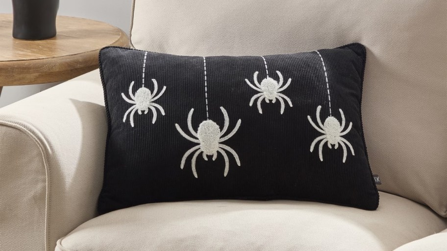 a black lumbar pillow with white spiders 