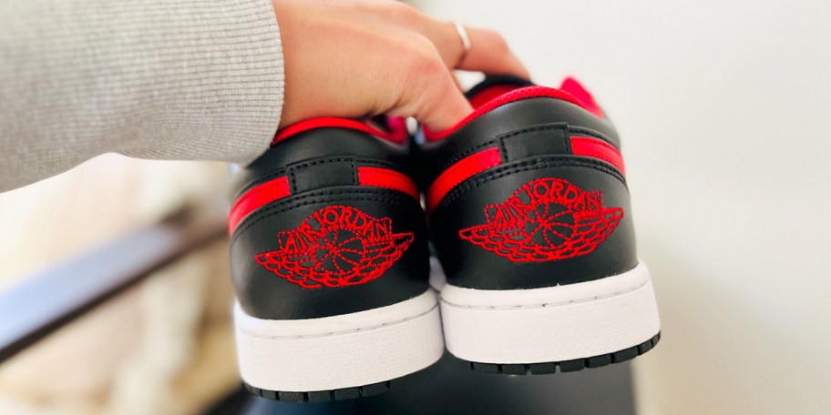 hand holding red and black jordan shoes 