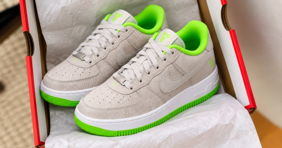 a pair of kids grey and green Nike Air Force 1 shoes in a shoe box