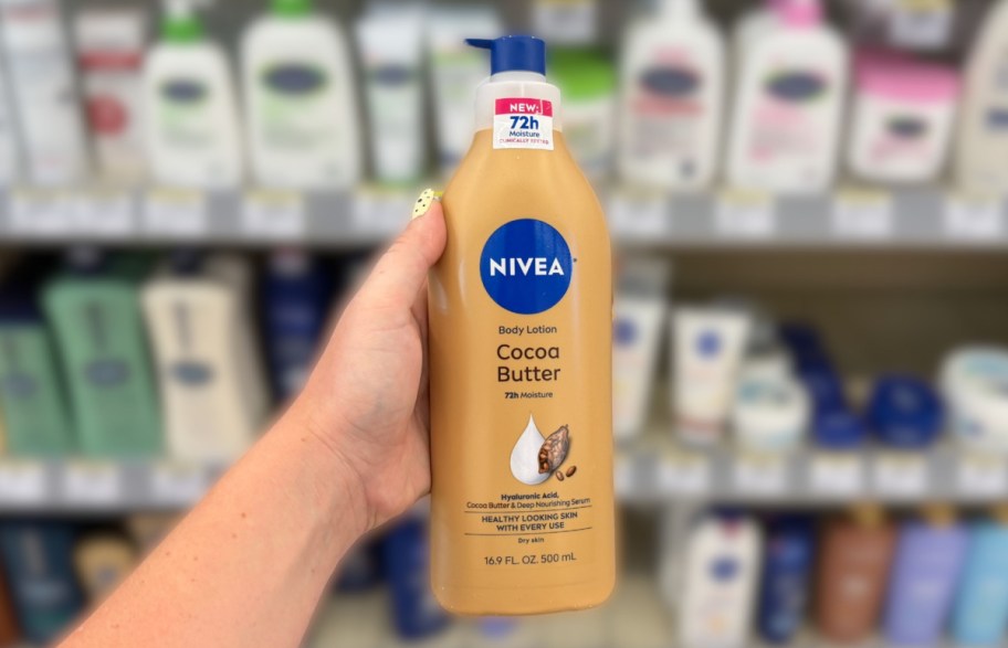 hand holding a bottle of body lotion in front of a store shelf