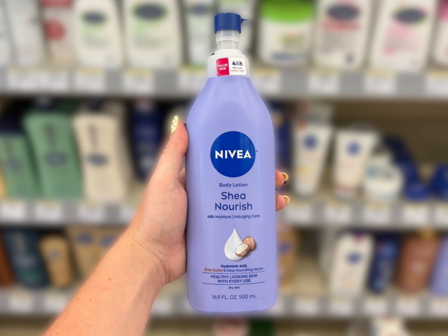 hand holding a bottle of body lotion in front of a store shelf