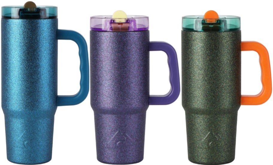 Three sparkly Ozark Trail 30oz tumblers with handles displayed side by side, featuring blue on the left, purple in the middle, and dark green with an orange handle and lid accent on the right.