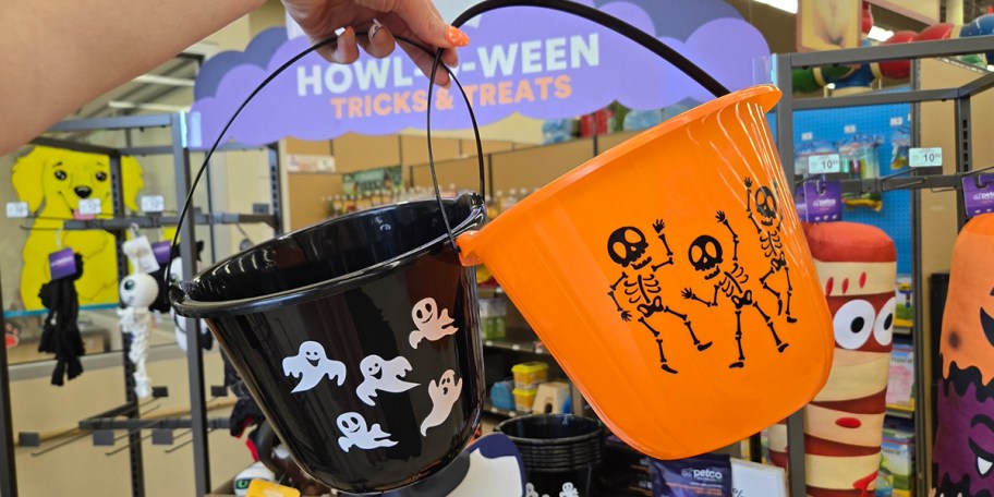 hand holding black ghost and orange skeleton buckets 