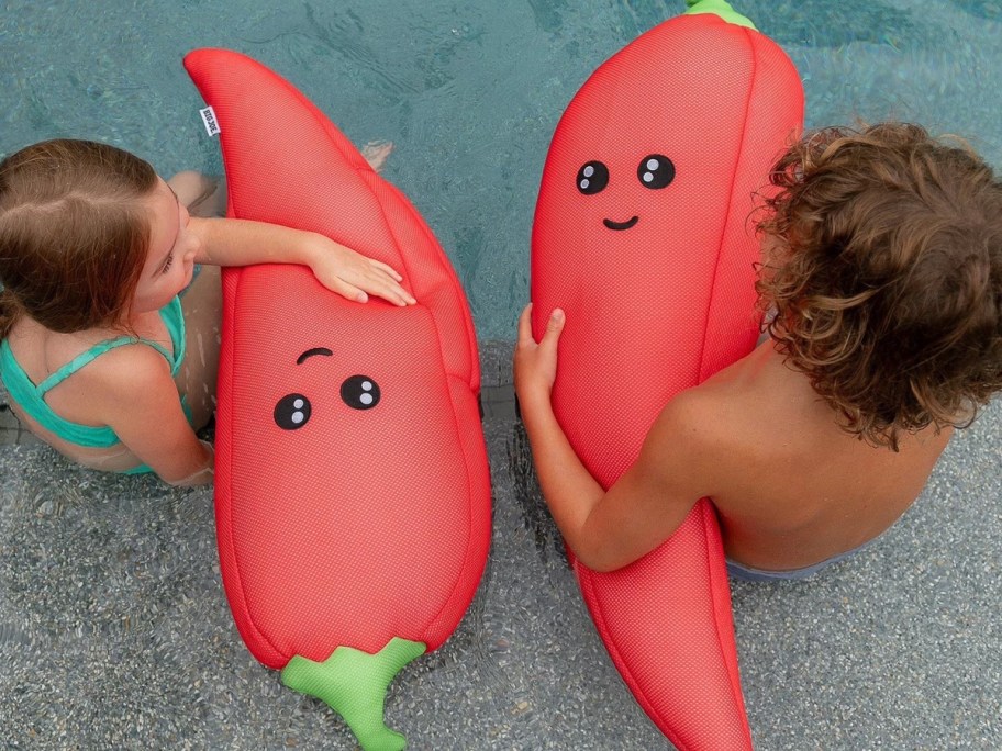 2 kids holding carrot pool floats in a pool