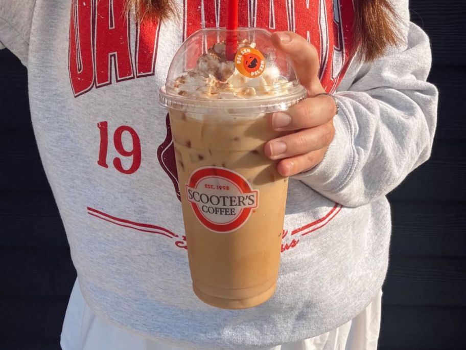 woman holding iced scooters coffee cup