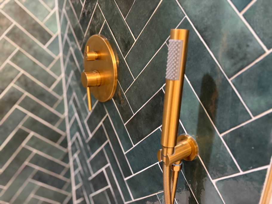 close up of gold shower hand wand in herringbone shower