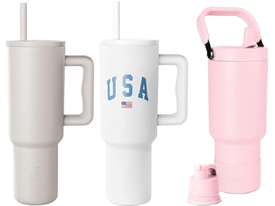 Three drinkware items displayed side by side: a solid taupe-gray tumbler with a handle and straw on the left, a white tumbler with a blue "USA" graphic, handle, and straw in the middle, and a light pink bottle with a top handle and an extra lid on the right.
