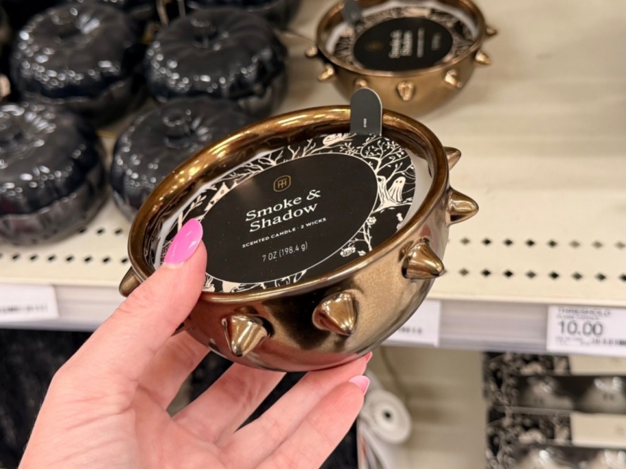 a womans hand holding a small spikey cauldron candle