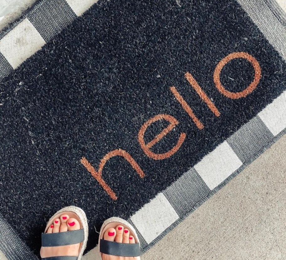 feet standing on black hello doormat