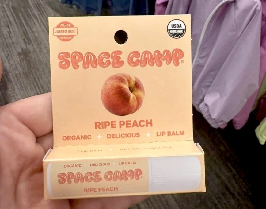 hand holding a package of space camp peach lip balm
