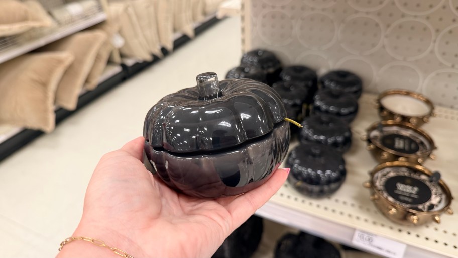 hand holding small pumpkin candle by store shelf