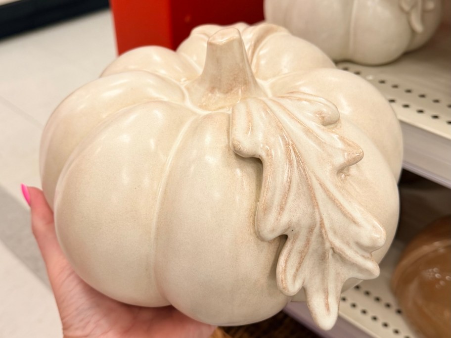 holding a white ceramic pumpkin