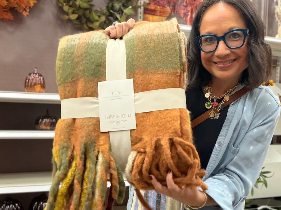 woman holding orange plaid blanket 