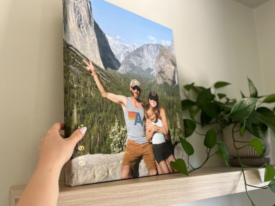 hand reaching for a canvas photo print on a wall shelf