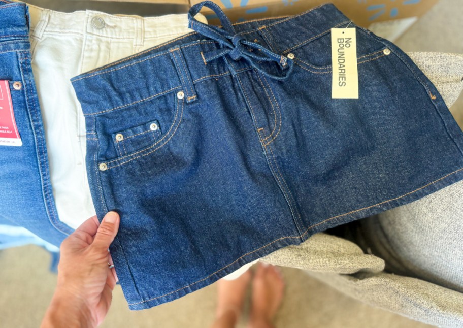 hand grabbing dark wash denim skirt on box
