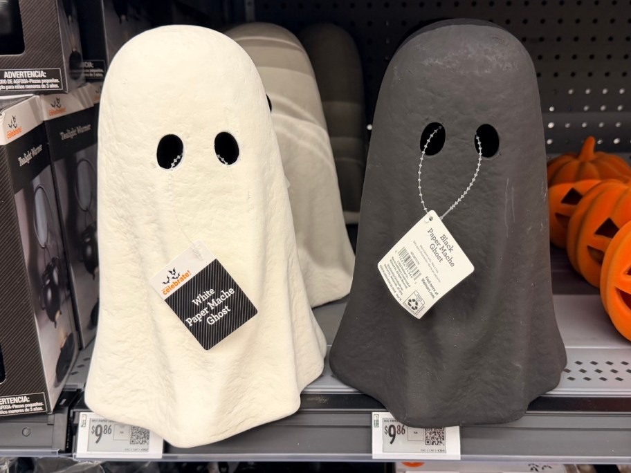 a white and a black paper mache Halloween ghost decoration on a store shelf