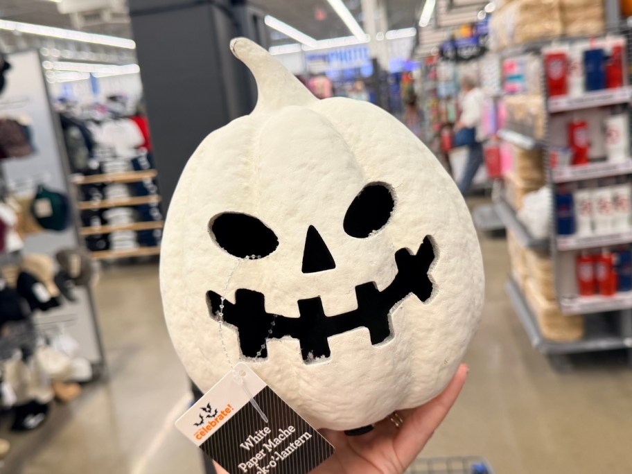 hand holding a white paper mache jack-o-lantern in a store