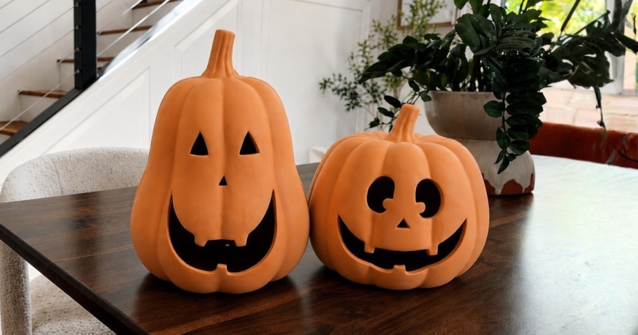 two terracotta pumpkin decorations sitting on dining room table
