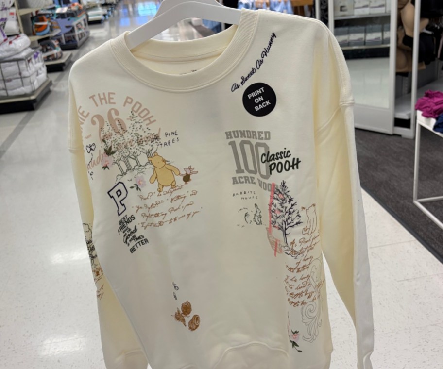 beige winnie the pooh sweatshirt on a white hanger