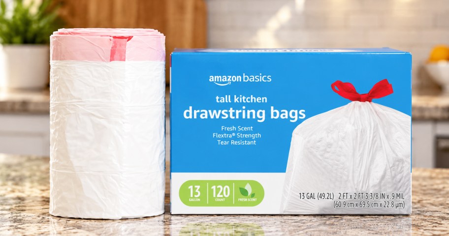 blue box of Amazon Basics 13-Gallon Trash Bags on kitchen counter next to roll of trash bags