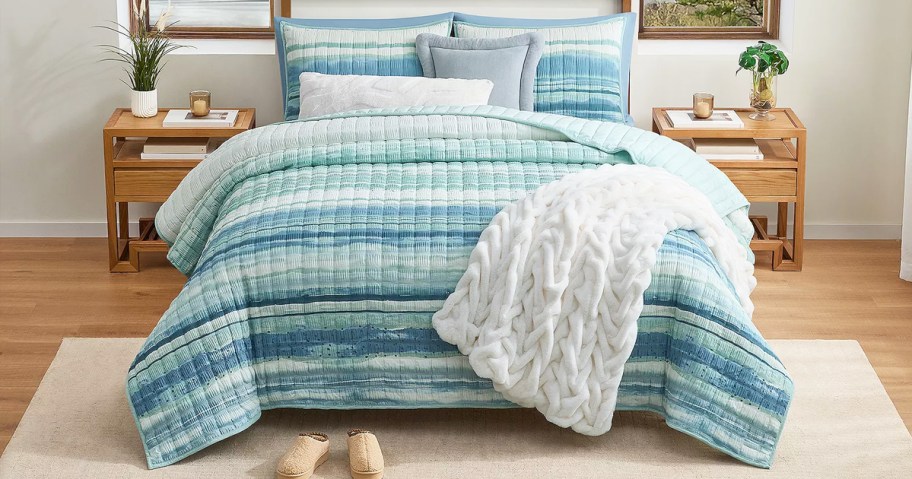 blue and white quilt set on a bed with matching shams and a throw blanket