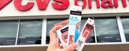 hand holding cosmetics up in the air in front of a cvs storefront