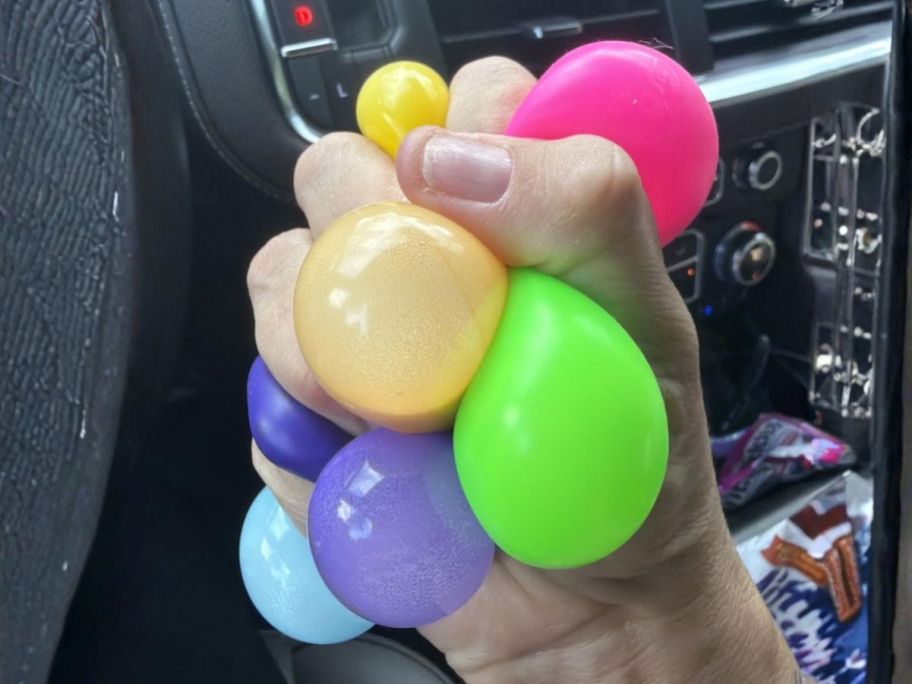 hand squishing Crayola Globbles Fidget Toy 6-Pack in car