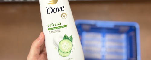 hand holding a bottle of Dove Cucumber & Green Tea Body Wash in store aisle