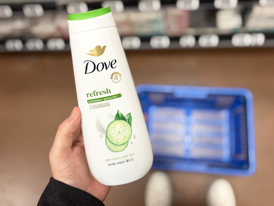 hand holding a bottle of Dove Cucumber & Green Tea Body Wash in store aisle