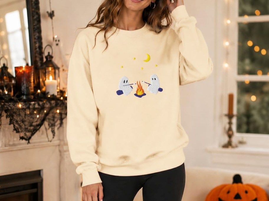 woman wearing sweatshirt with ghosts roasting marshmallows design