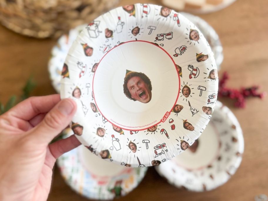 Hand holding an Elf plate with other plates in the background