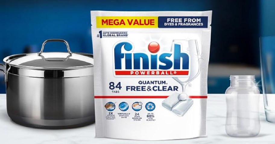 Bag of finish, quantum free and clear dishwasher pods next to pots and pans