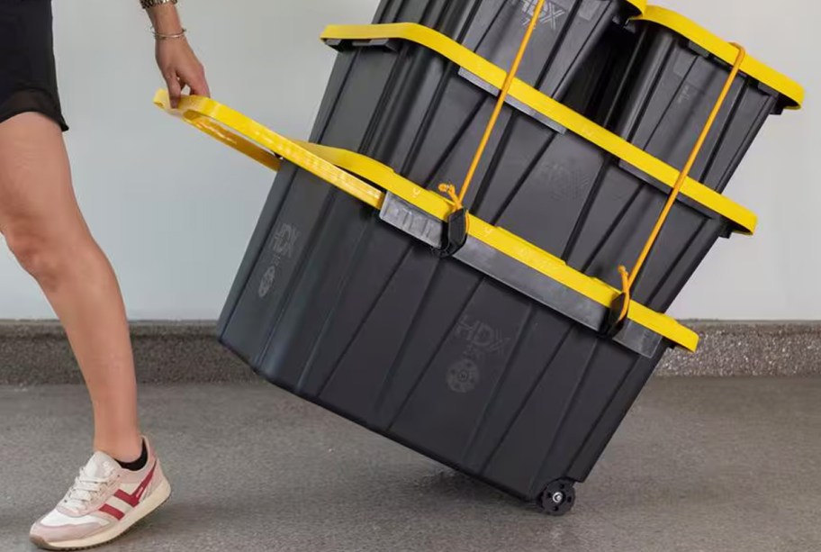 woman rolling a large storage tote with more totes stacked on top