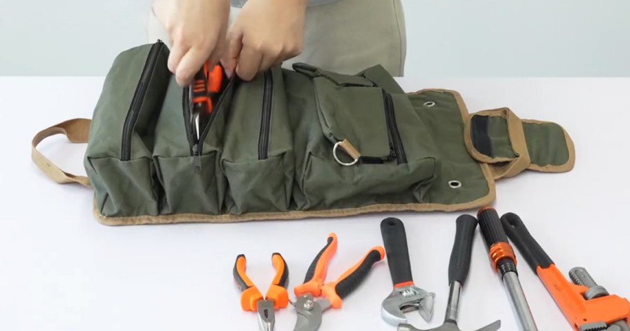 man placing tools into a roll up tool bag