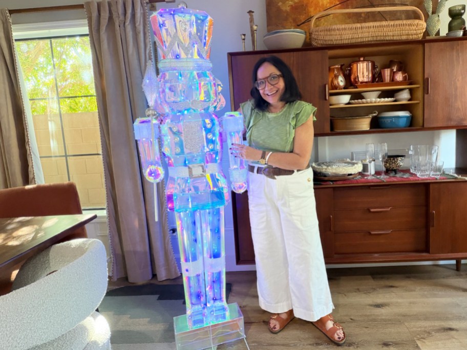 woman standing next to a tall iridescent nutcracker decoration