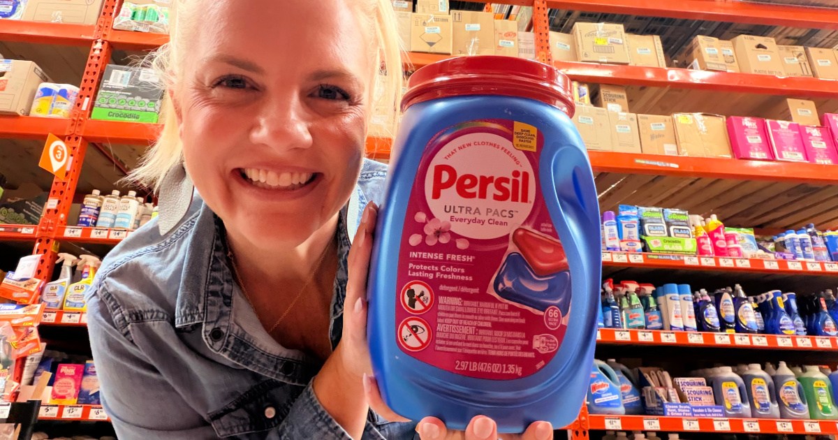 Woman holding up container of persil laundry detergent, ultra packs inside Home Depot store