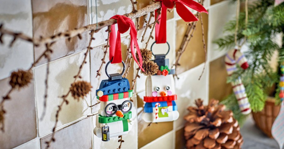 LEGO Snowman Ornaments hanging from a branch by red ribbons