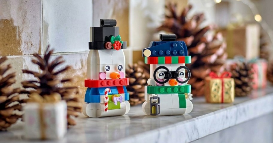 two LEGO snowman ornaments on a mantel