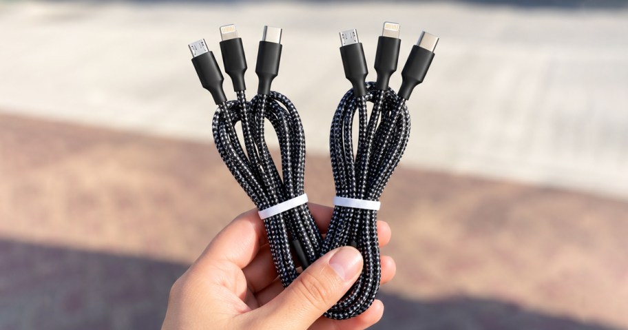 hand holding up two black charging cable sets