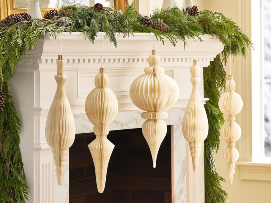 white honeycomb paper ornaments hanging from a mantle