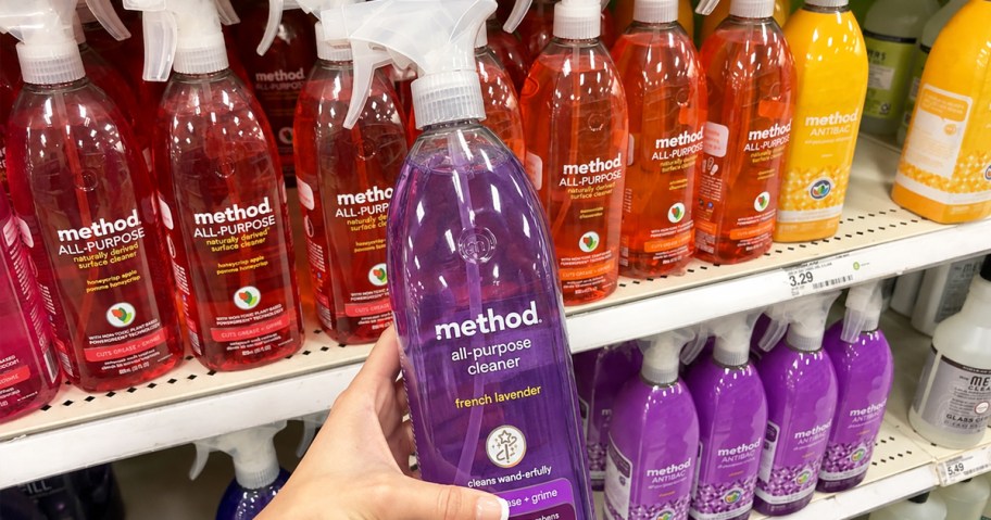 hand holding up a purple bottle of Method All-Purpose Cleaner Spray in store aisle