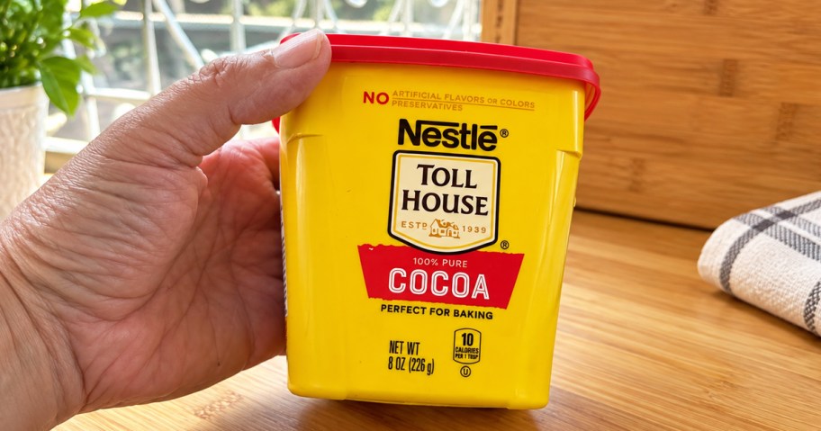 hand holding a yellow and red container of Nestle Toll House Cocoa Powder