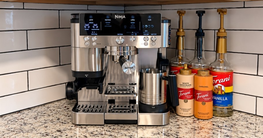 a Ninja Espresso Machine next to bottles of coffee syrup on a kitchen counter